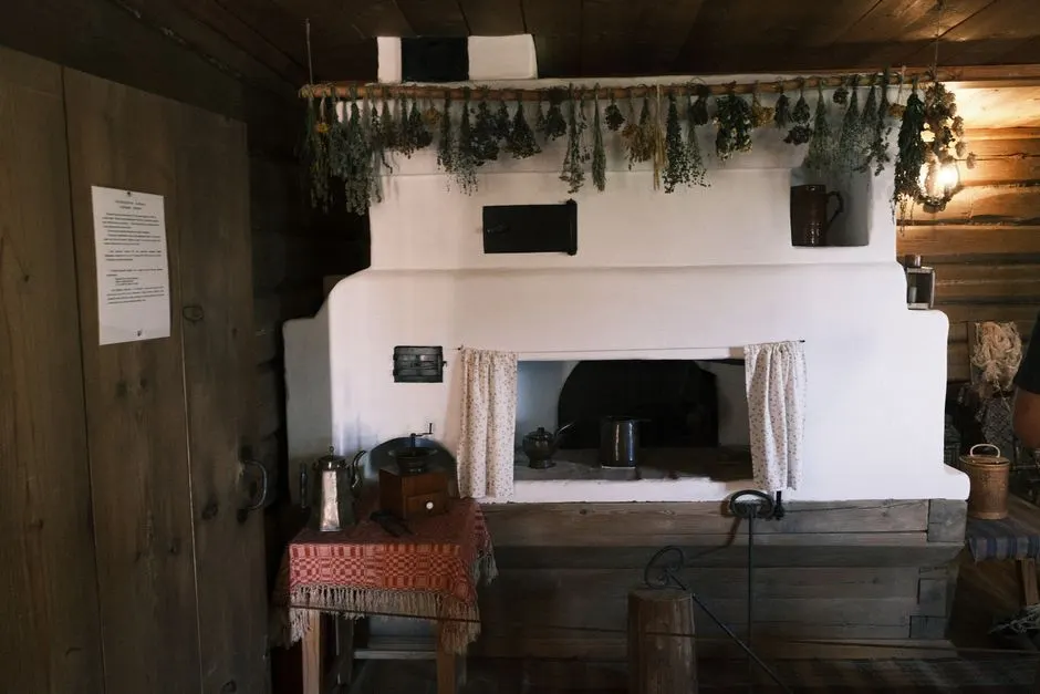 Cozy rustic room with traditional fireplace, hanging herbs, and wooden furnishings, capturing a vintage homely feel.